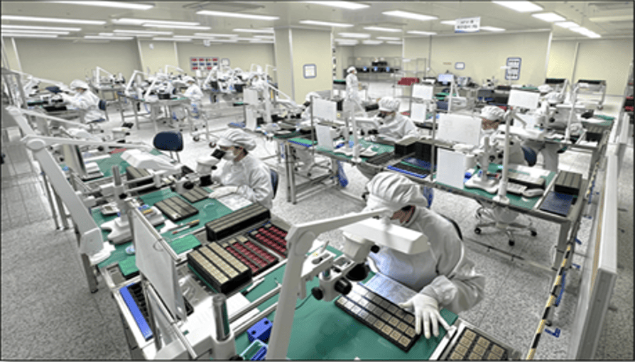 Workers in a clean room inspecting items with microscopes